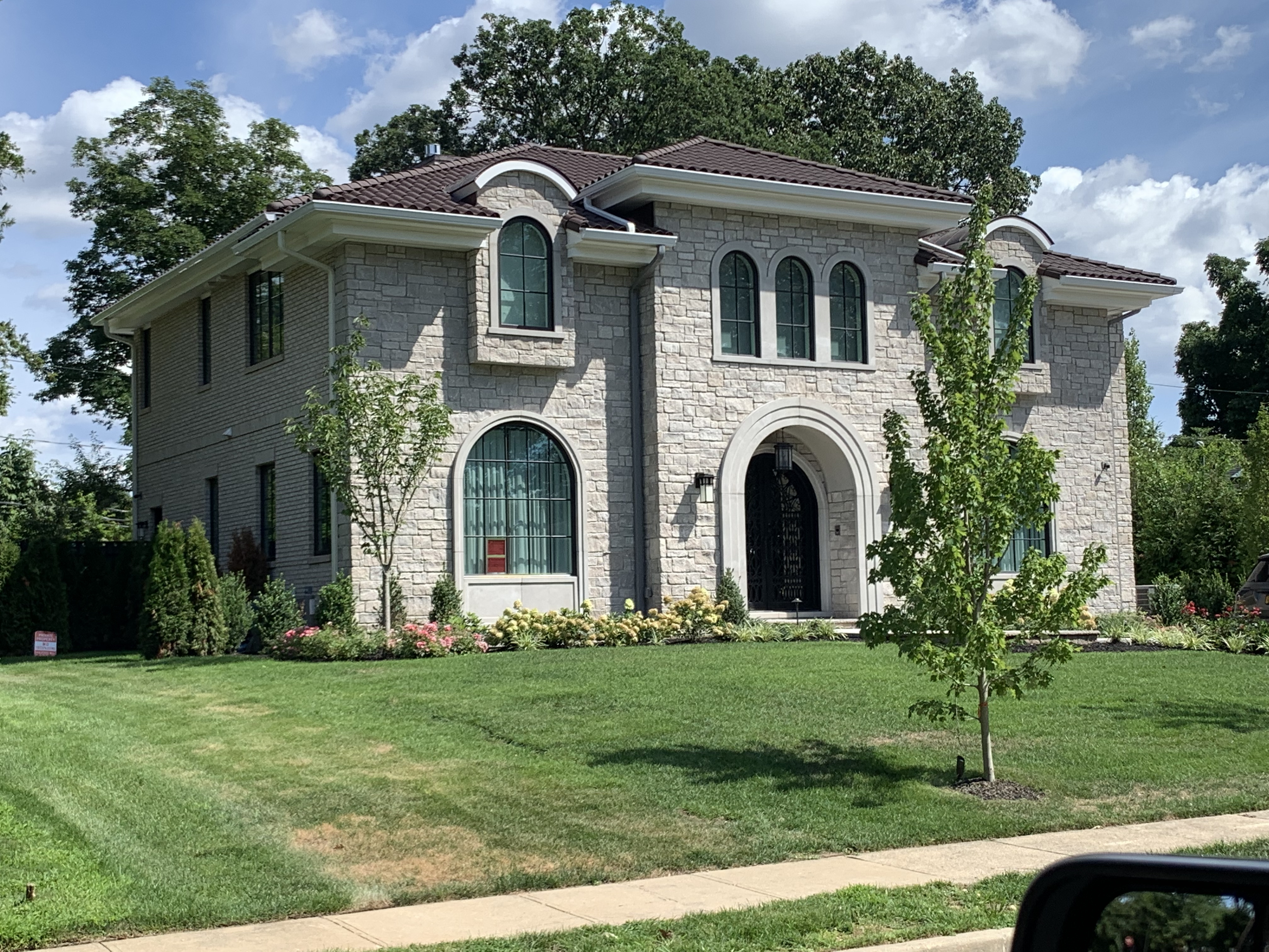Stone mansion with brown clay tile roof and landscaped grounds