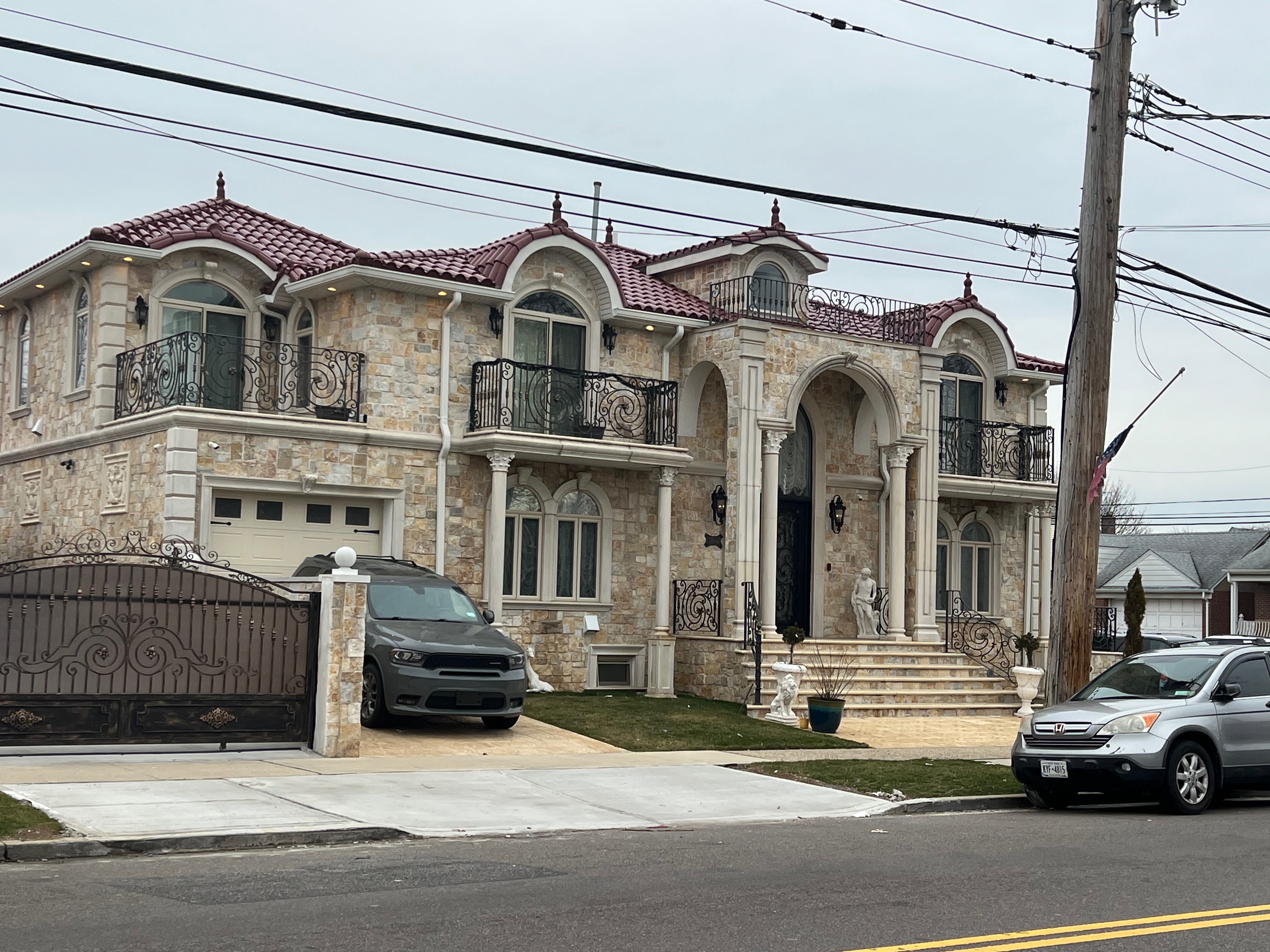Mediterranean-style luxury mansion with natural stone exterior and rich burgundy S-shaped clay tile roofing