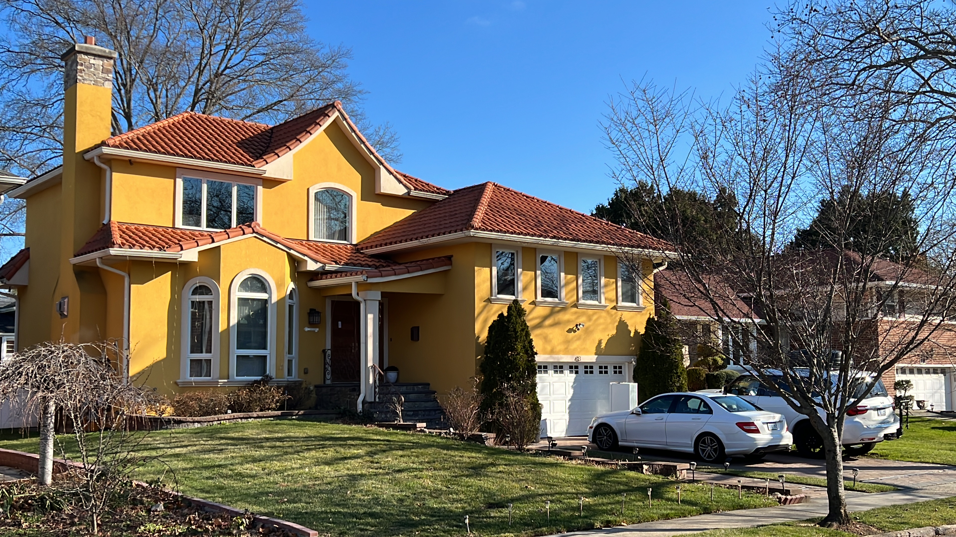 Mediterranean-style home with vibrant golden yellow exterior and classic reddish-brown terracotta S-shaped clay tile roofing